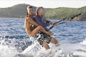 A naked woman riding back of Richard Branson on a water glider