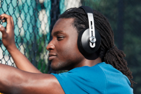 Profile of a man wearing headphones sitting near a wire fence