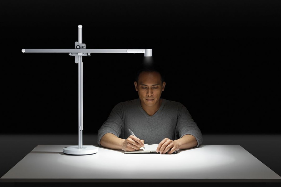 Man writing next to Dyson Lightcycle Task Desk Light