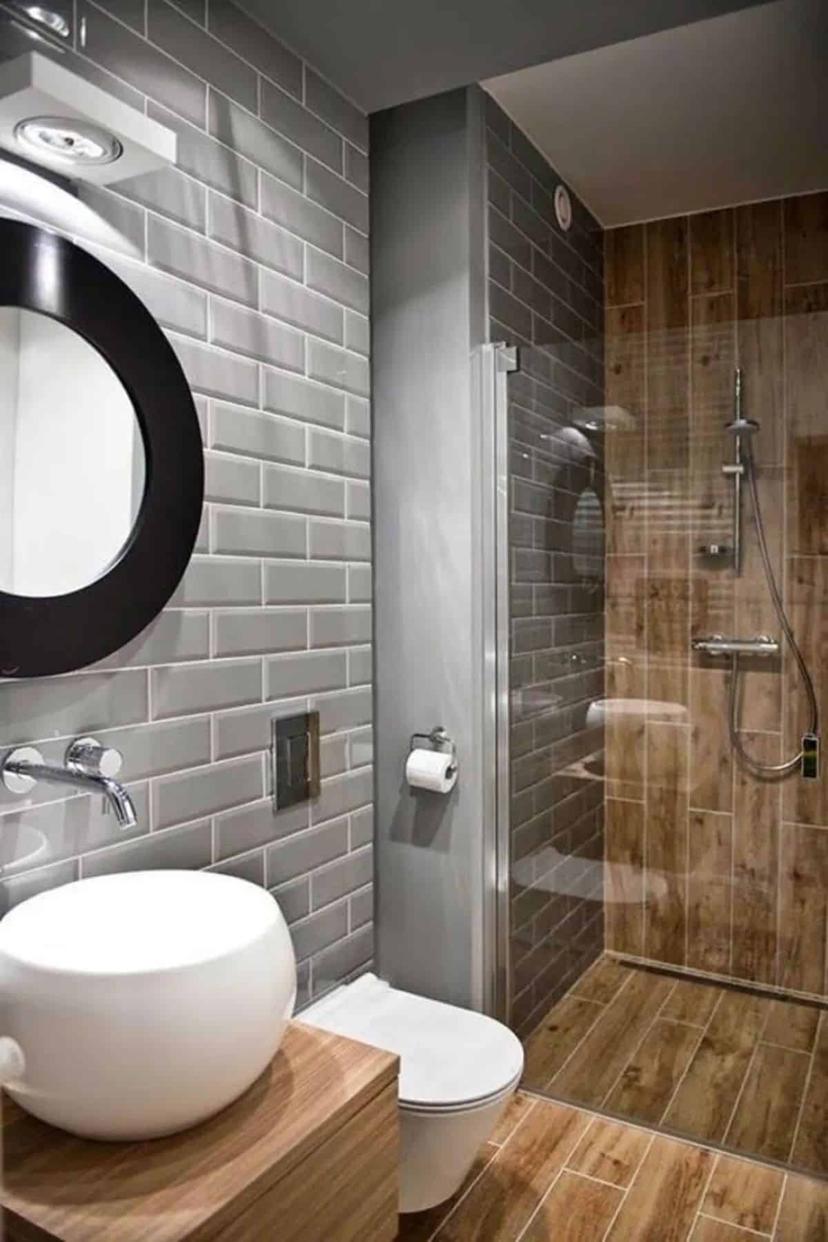 Grey masonry wall bathroom with wood wall in shower area