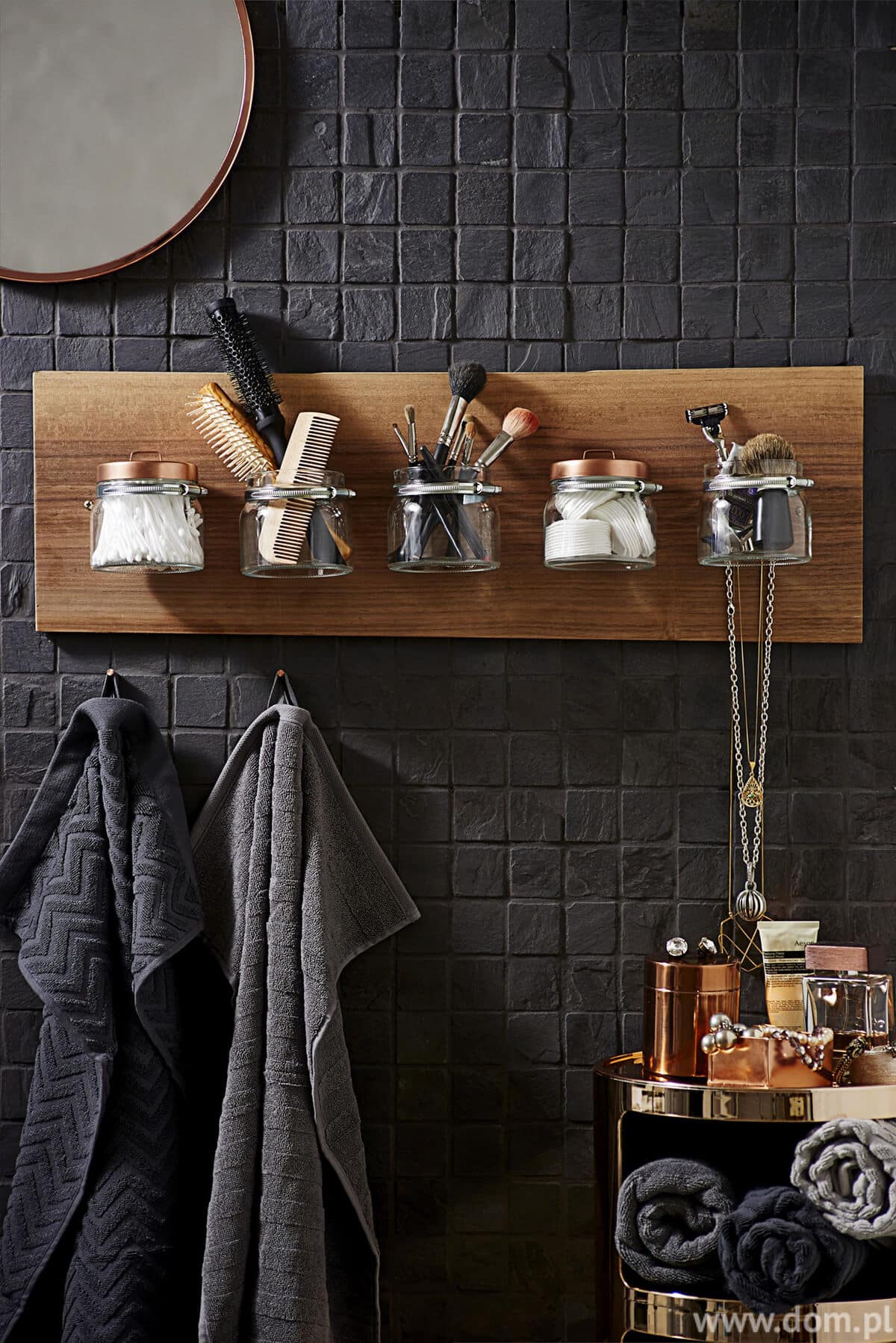 Bathroom supplies on wood jar holder on black masonry wall 