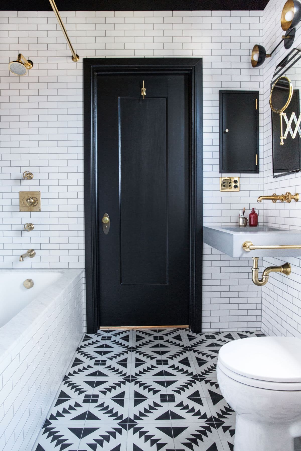 White masonry wall bathroom with black door and golden pipes, knobs, faucets and taps
