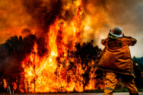 A Rural Fire Brigade Fireman in front of a large bushfire
