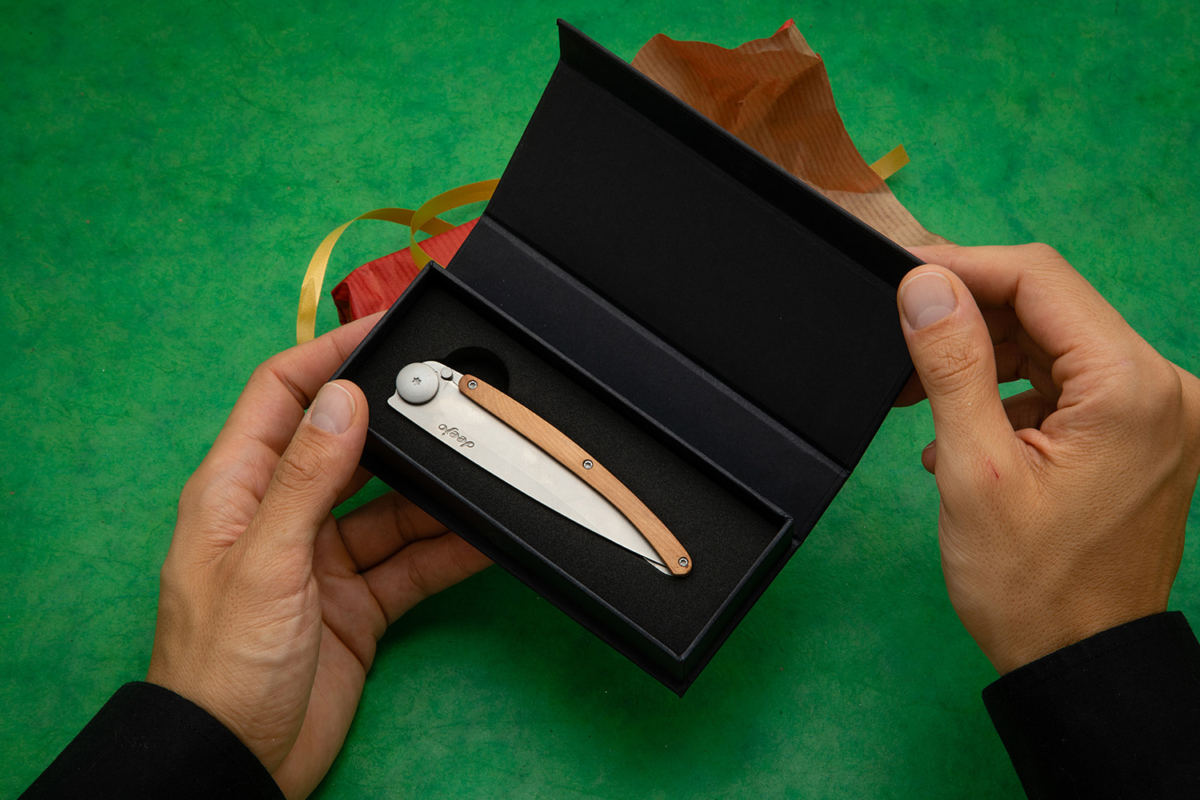 Pair of hands holding a Deejo knife in its box