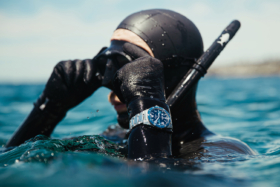 A diver in black wetsuit on surface wearing Glashütte Original watch