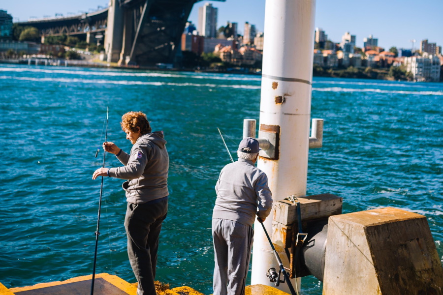 Two men with fishing rods under Sydney Harbour Bridge