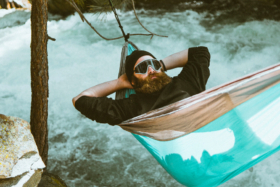 A man sleeping in a hammock over a water stream