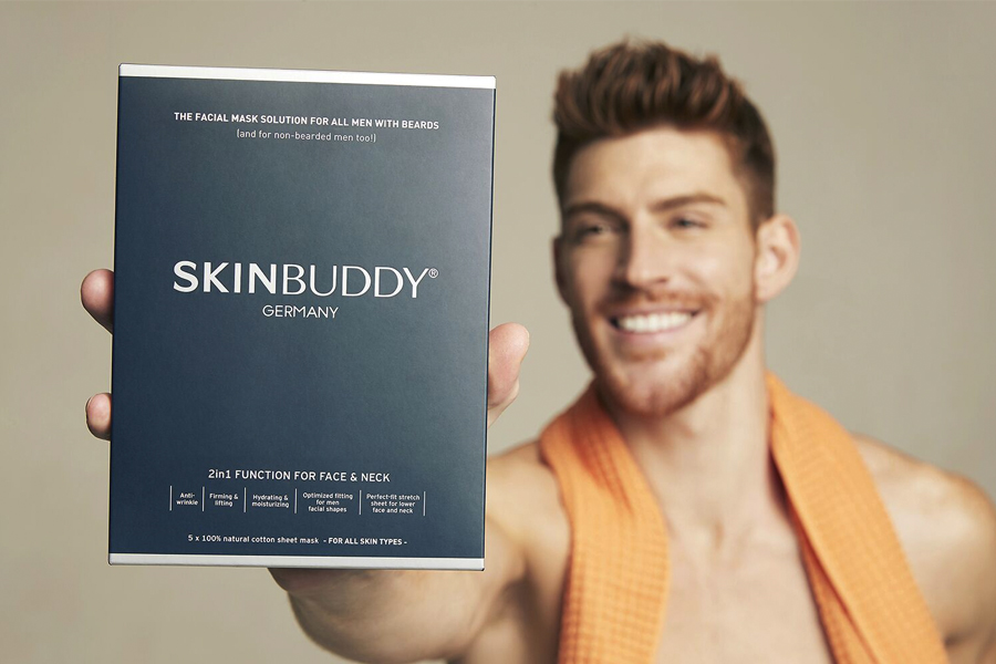 A man holding a box of SKINBUDDY Facial mask for bearded man in front