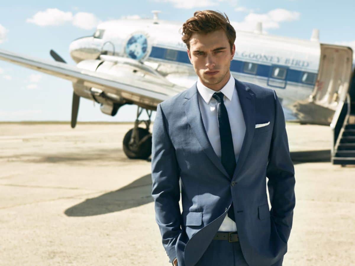 Man in a grey suit and a plane in background