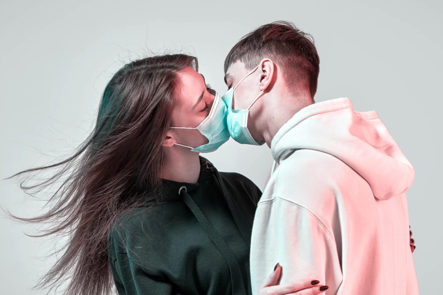 A man and woman kissing with masks on