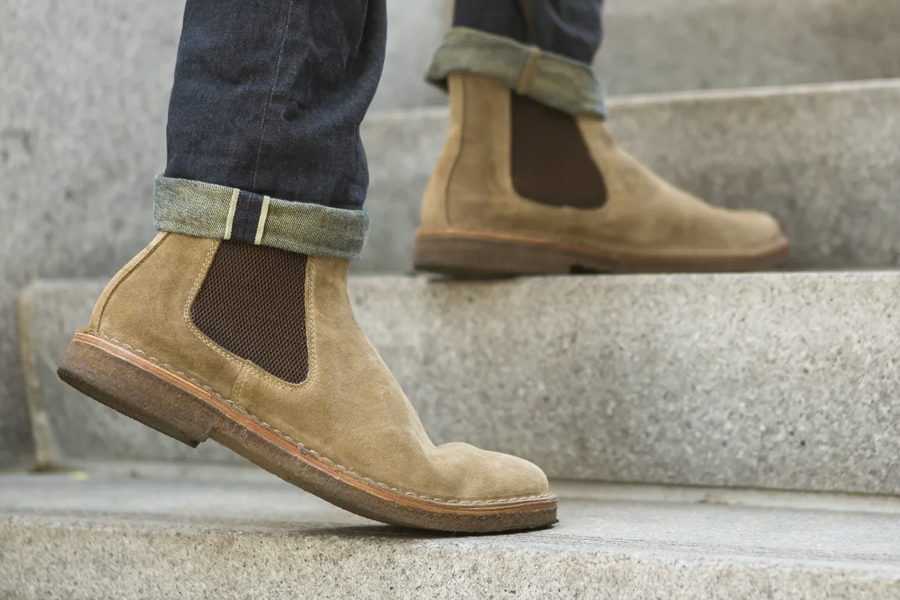 A pair of feet in brown Chelsea boots on stairs