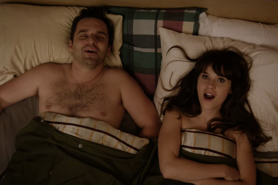 A movie scene with a surprised actress and happy actor in bed