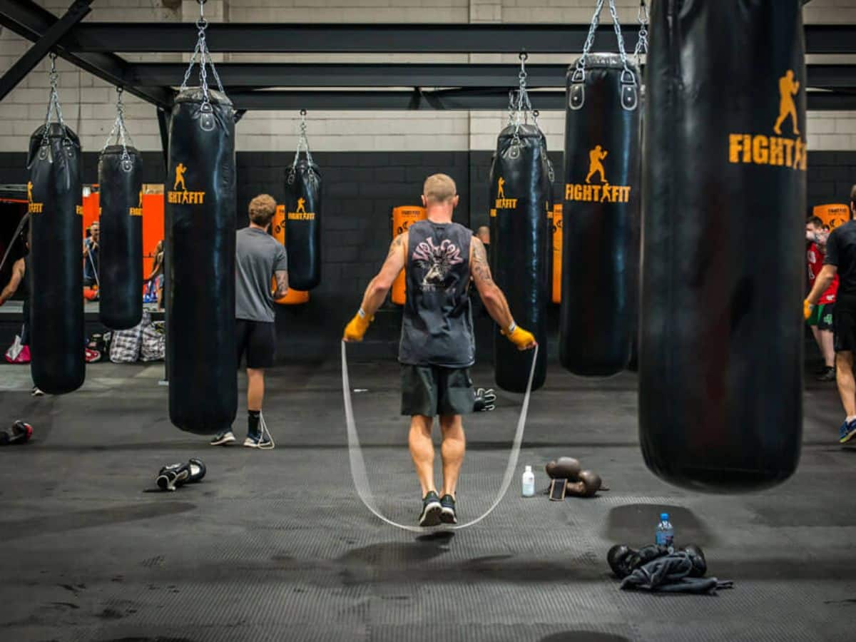 Back of a man skipping ropes with punching bags hanging around him at Fight Fit Boxing Centre