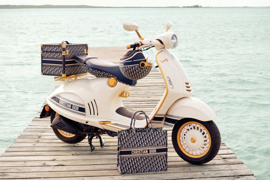 Vespa 946 Christian Dior edition and a Christian Dior bag on a wooden deck with water in background