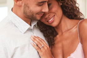 A woman with an engagement ring leaning on shoulder of a man