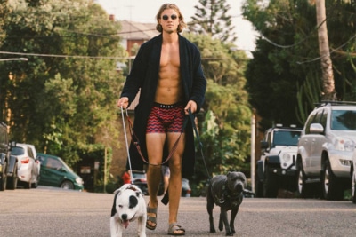 Male walking two dogs on a leash, wearing Sparx red and black striped underwear