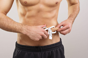 A man measuring belly flab thickness with a skin fold calipe