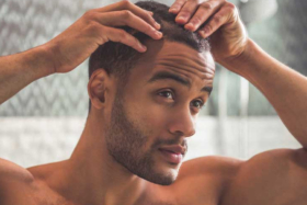 A man checking his scalp in mirror