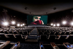 An empty cinema with a woman on screem