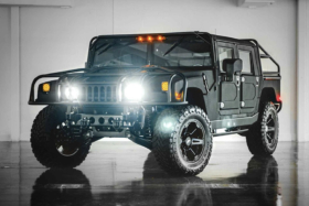 Three quarters front of Mil-Spec's Hummer H1 with headlights on