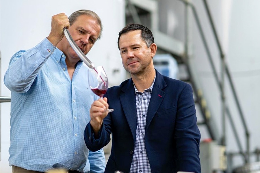 A man pouring wine in Ricky Ponting's glass from wine thief