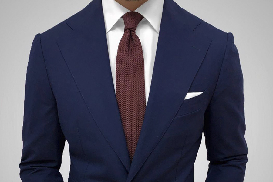 A torso of a man in suit with Dark Knot accessories