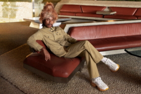 A model sitting on a couch wearing Moncler 1952 Men’s Collection khakhi clothes