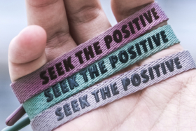 Three Rastaclat bracelets with "Seek the positive" in a palm