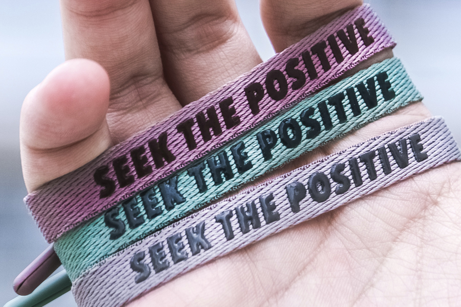 Three Rastaclat bracelets with "Seek the positive" in a palm