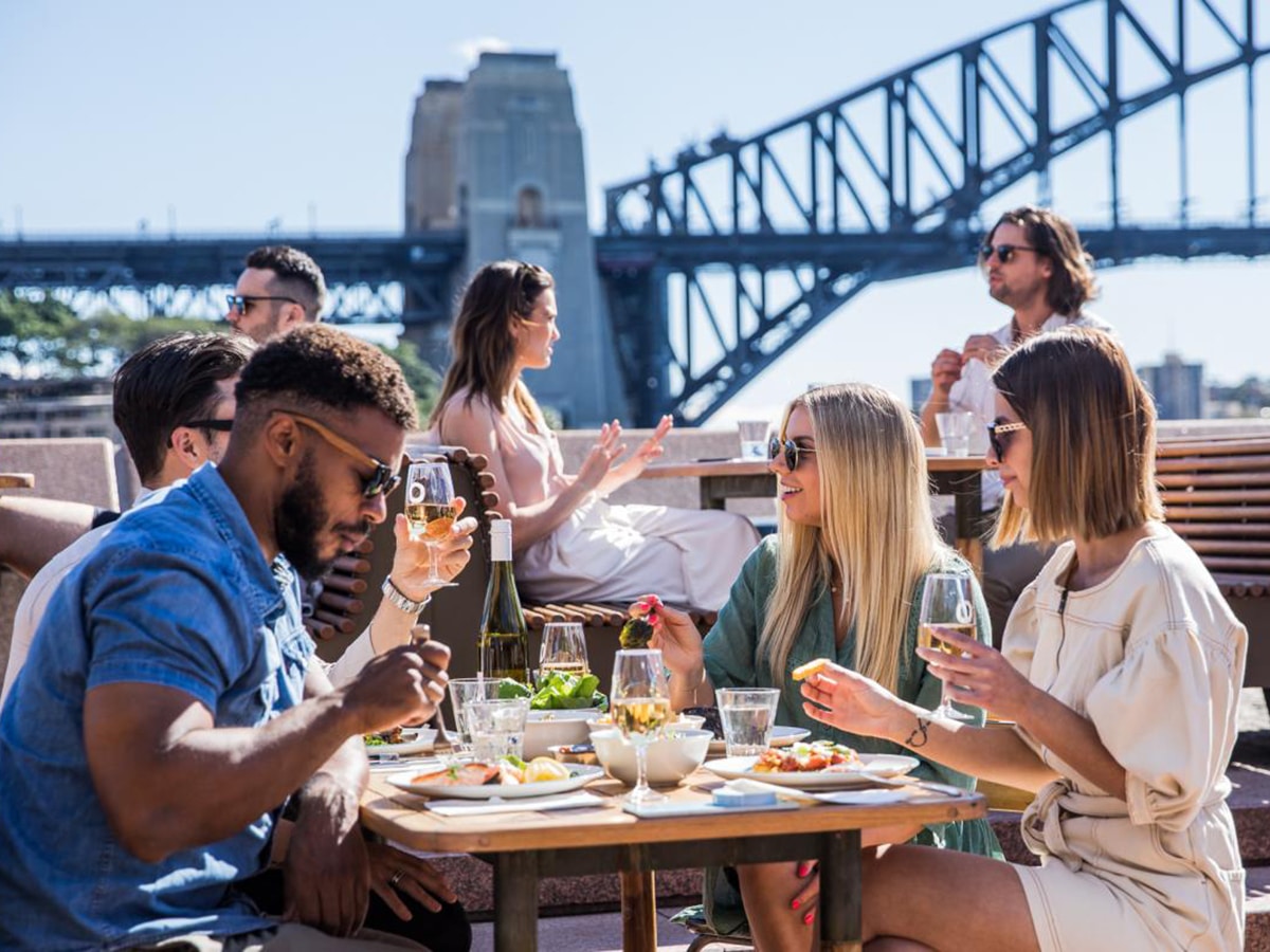 group of people eating at opera bar in front of sydney harbour bridge