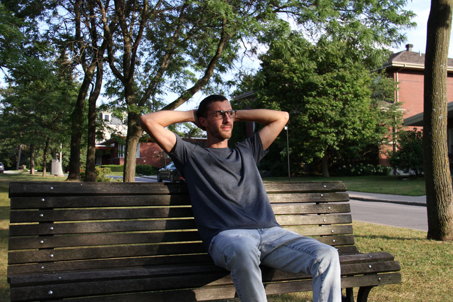 A man wearing Social Citizen t-shirt on a bench with his hands behind his head
