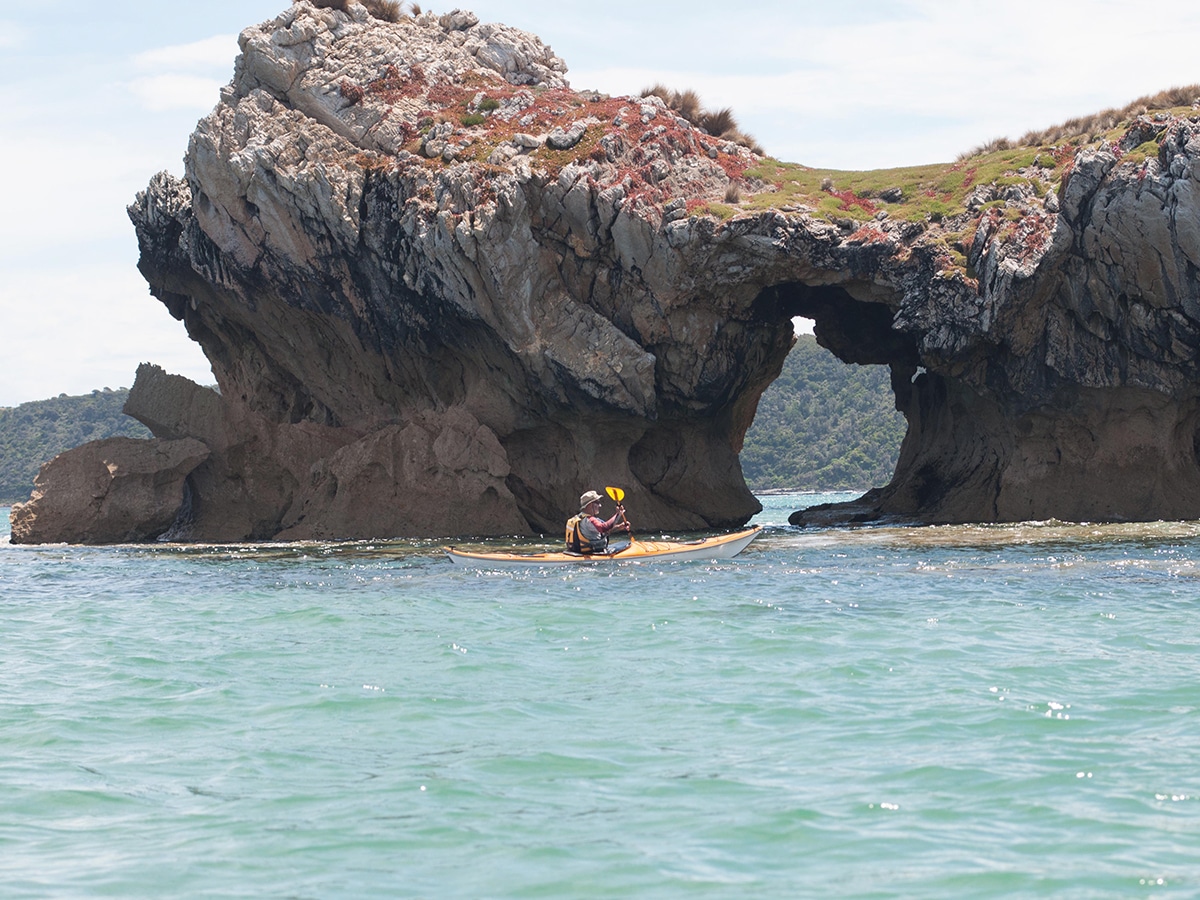 man kayaking near the shores of Waratah Bay