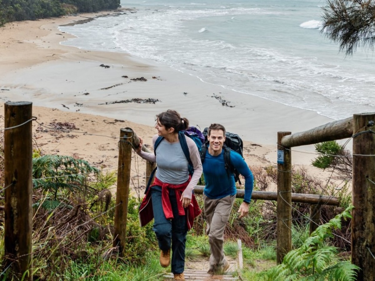 couple walking up on wooden stairs at blanket bay great otway national park