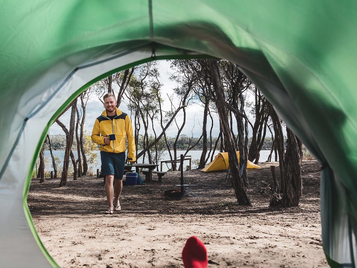 smiling man walking to tent at bunga arm gippsland lakes coastal park
