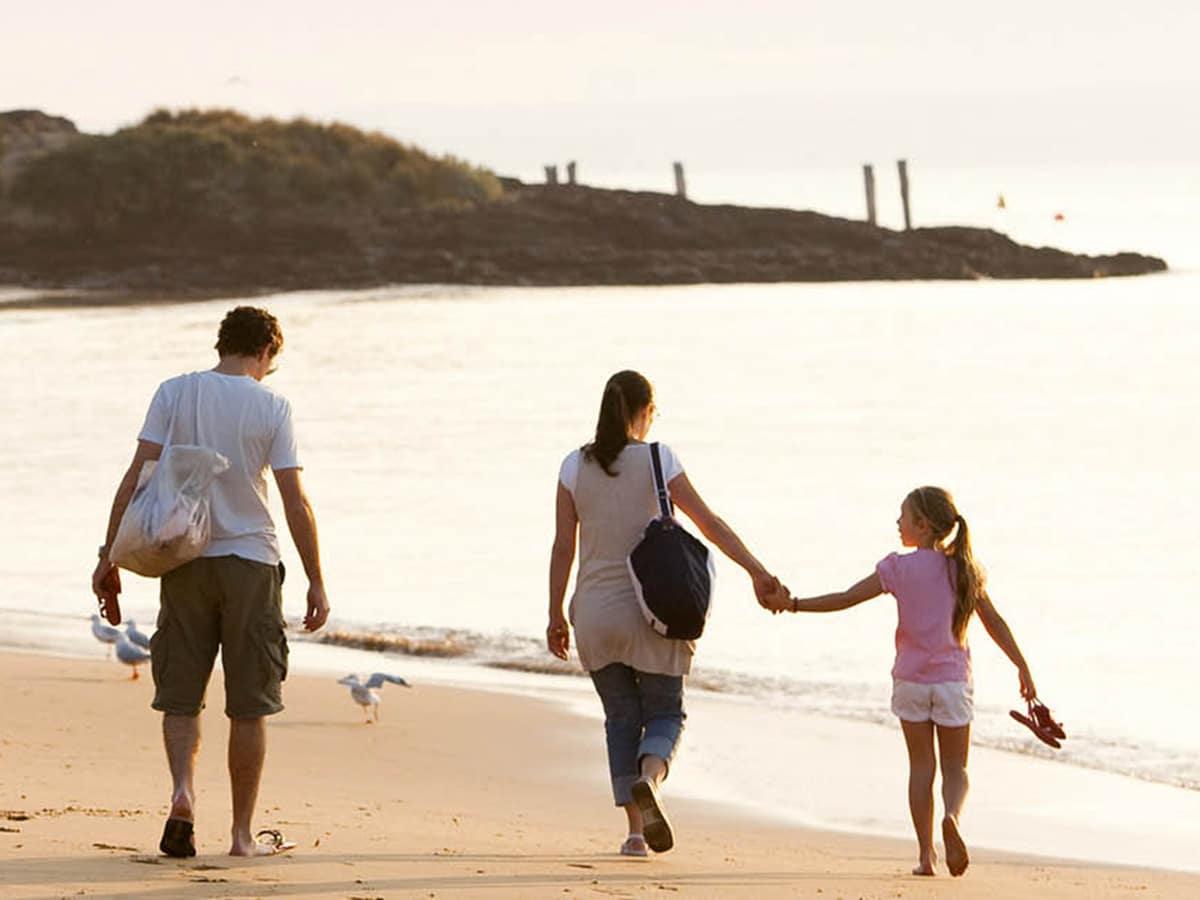 couple with kid walking on newhaven beach phillip island