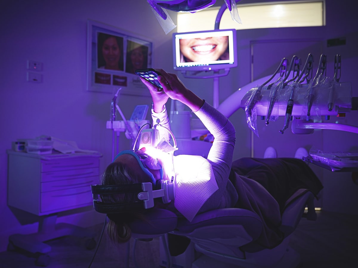 woman on a dentist's chair getting teeth whitening treatment at cosmetic laser dentistry centre
