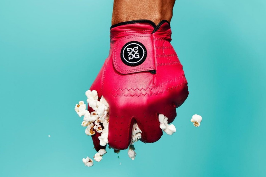 A hand wearing G/FORE collection golf glove squeezing popcorn in fist