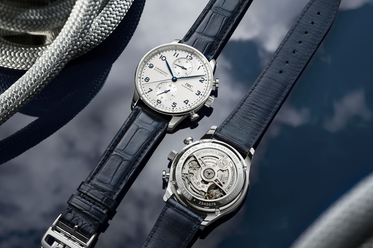 Two IWC Portugiesers on table. One with dial on top and one with caseback on top