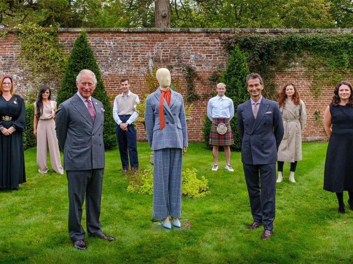 Prince Charles, Federico Marchetti and students who designed clothes in a lawn with a mannequin wearing clothes from The Modern Artisan project