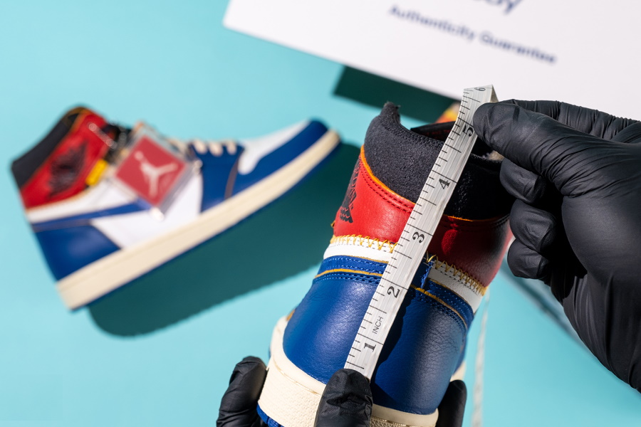 A pair of hands measuring the height of a sneaker rear support