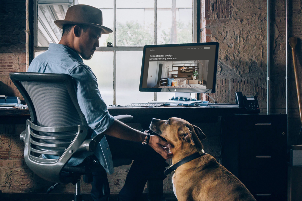 A man rubbing his dog's neck from his chair