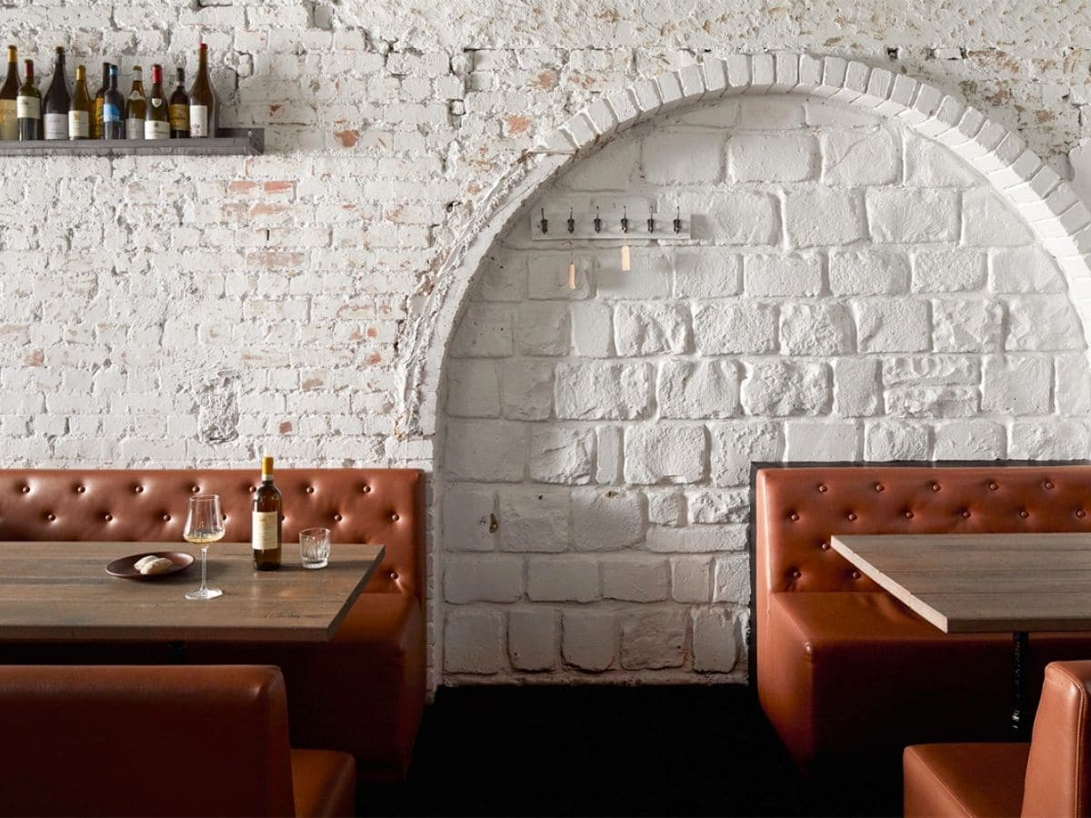 Interior of Osteria Ilaria restaurant with white and rust colour scheme showing tables and chairs