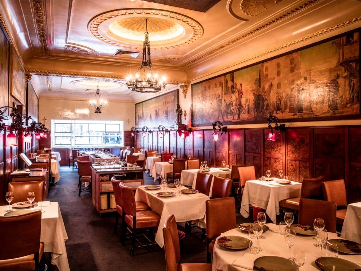 Interior of Florentino restaurant with classic brown and cream colour scheme showing tables, chairs, chandeliers and paintings on the walls