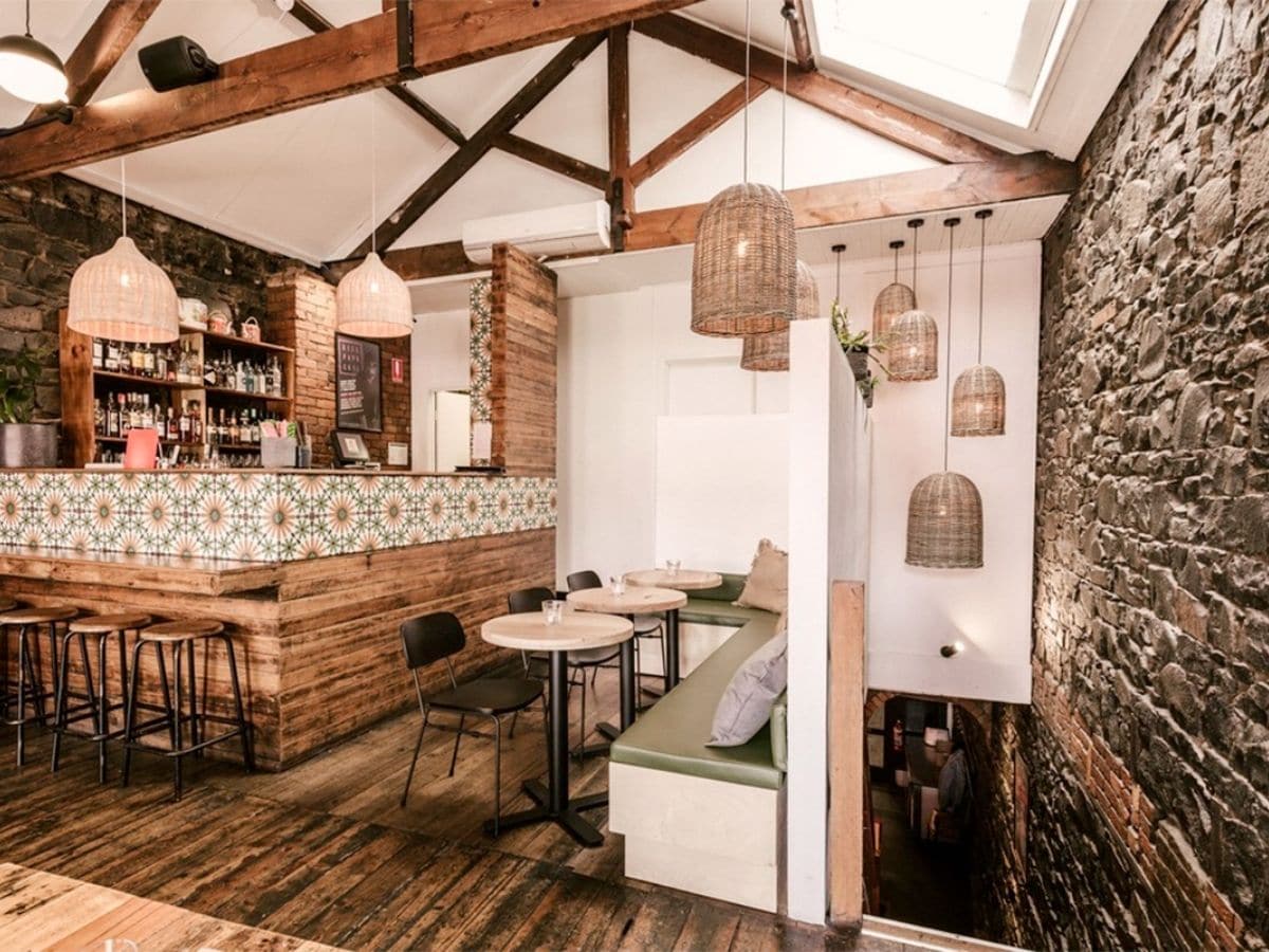 Interior of Rice Paper Scissors restaurant with white and cream colour scheme and wood accents showing tables, chairs and bar area