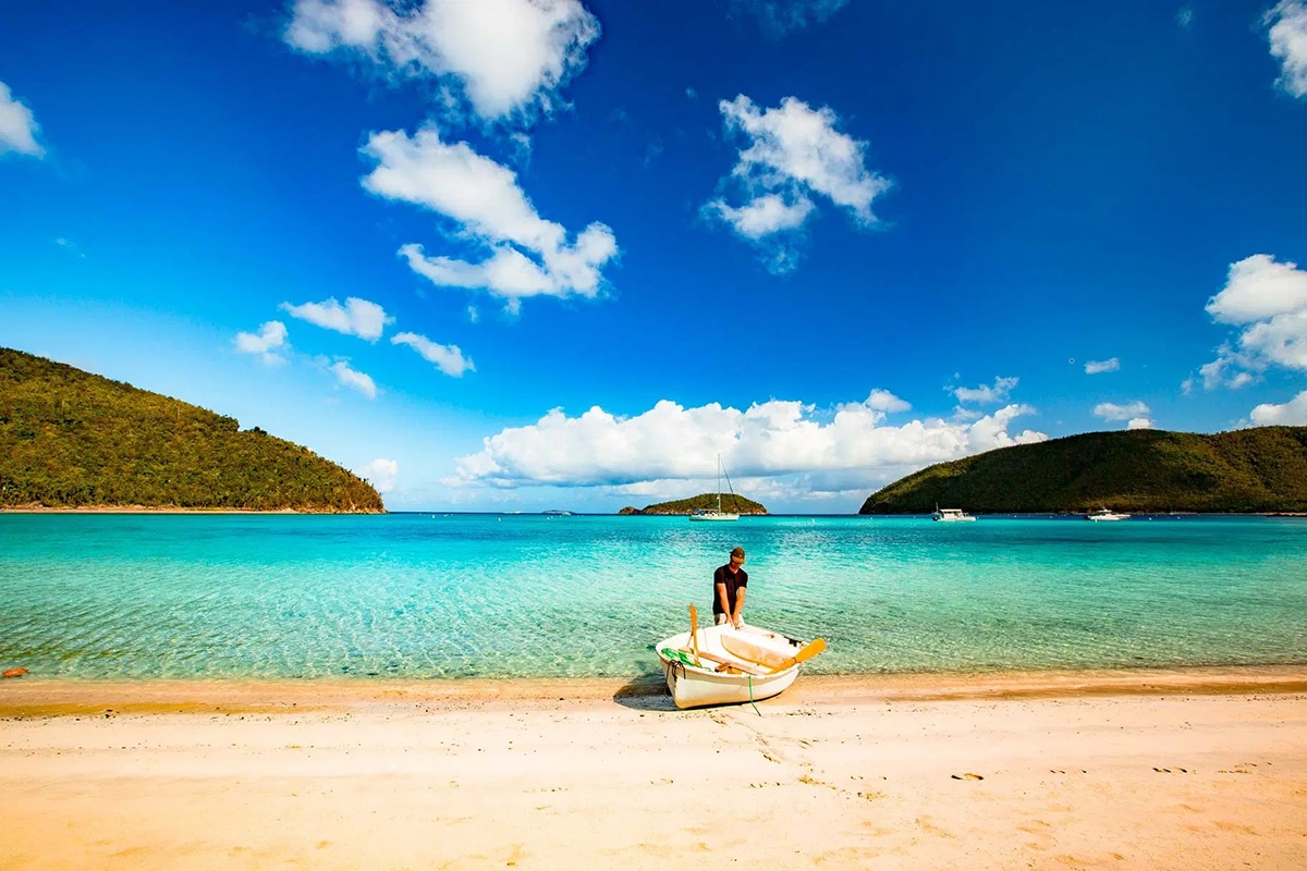 man pulls a boat on the maho bay beach