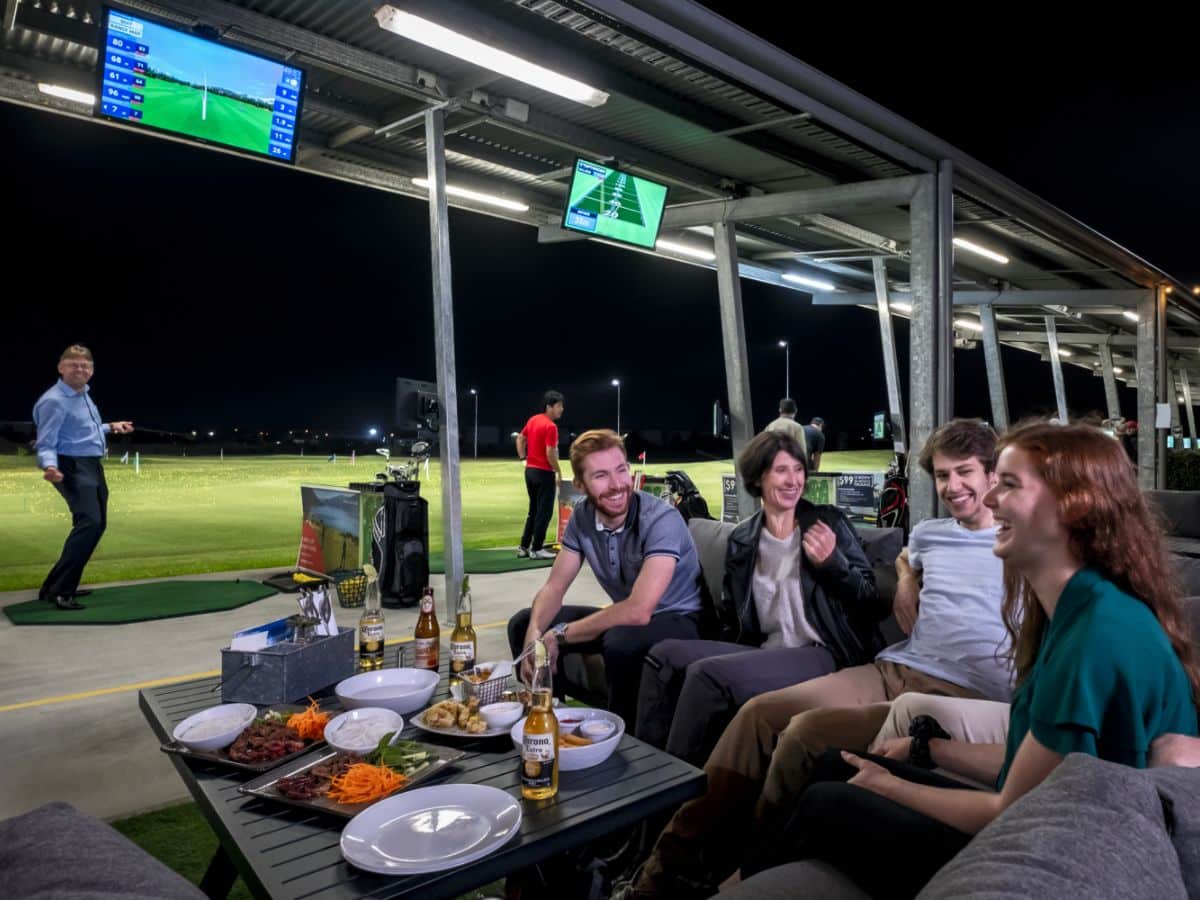 Group of friends sitting on a couch at driving range