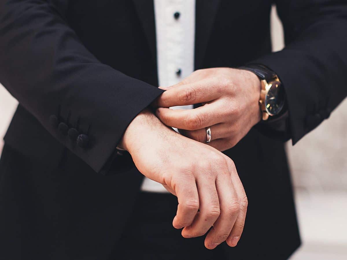 Man's hand with a wedding ring adjusting cuff of suit