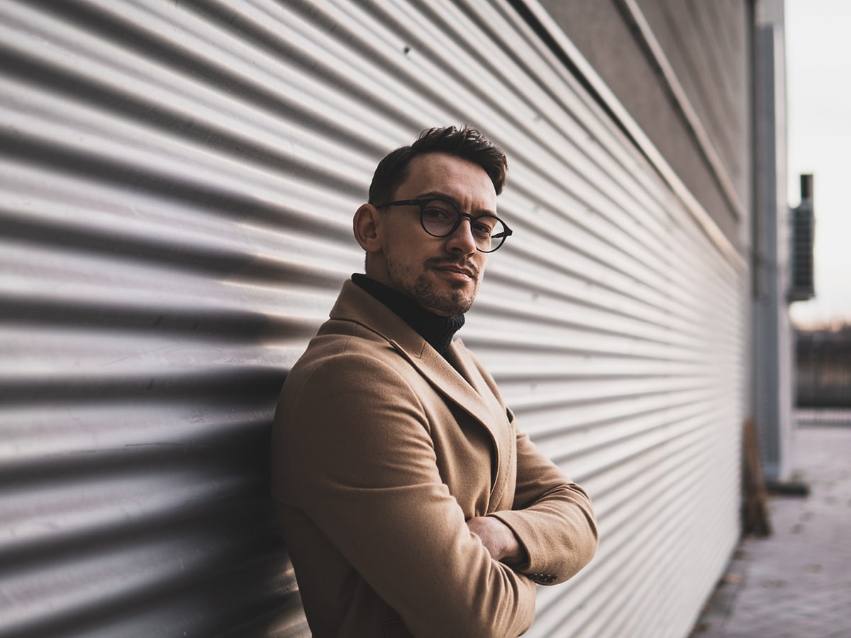 young man standing next to a metallic wall