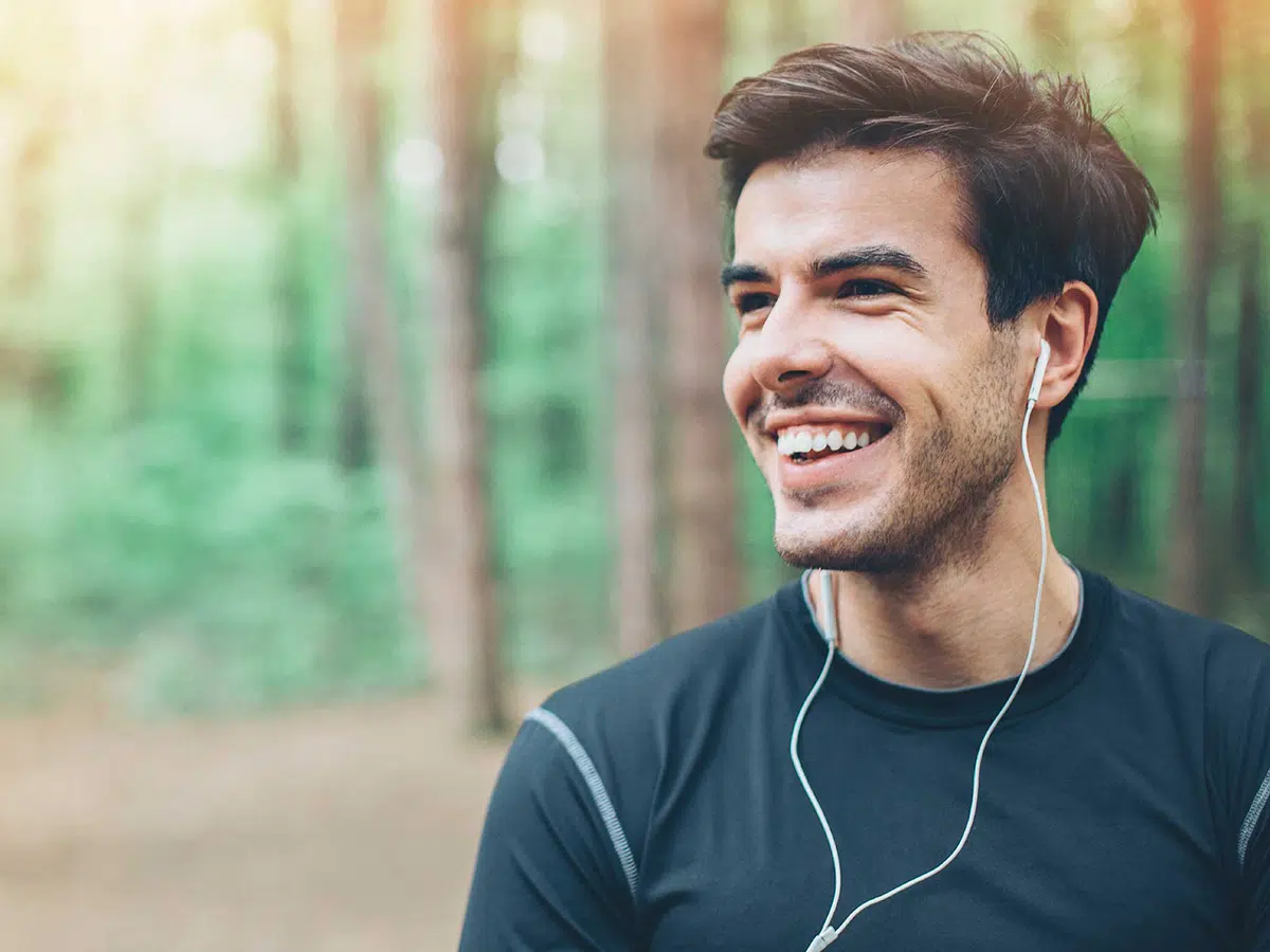 boldog ember fülhallgatóval az erdőben