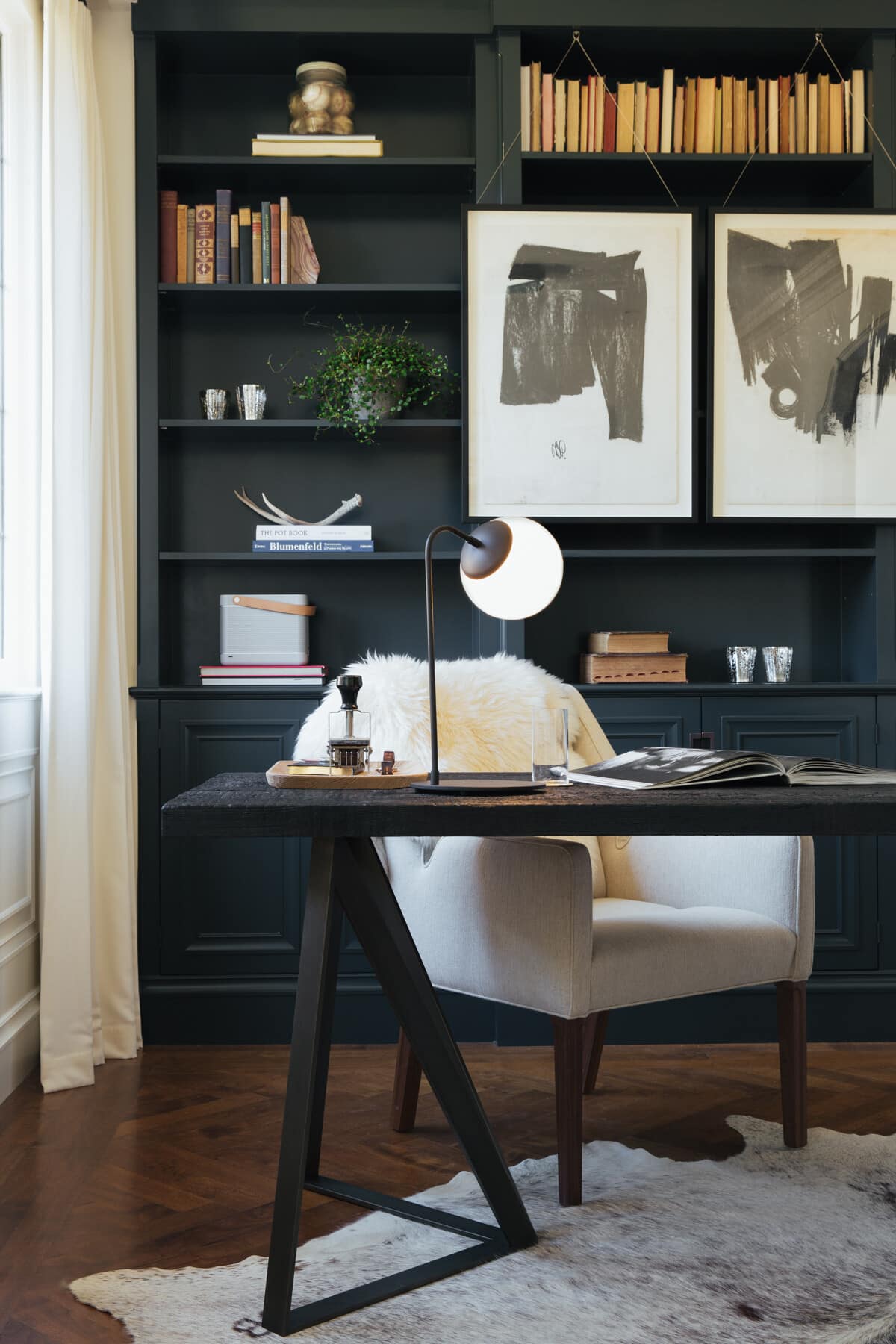 Black cabinet wall behind an office table and a fur headrest white cushioned armchair at table